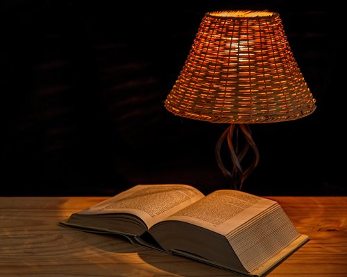 book on a wooden table with warm lamp light