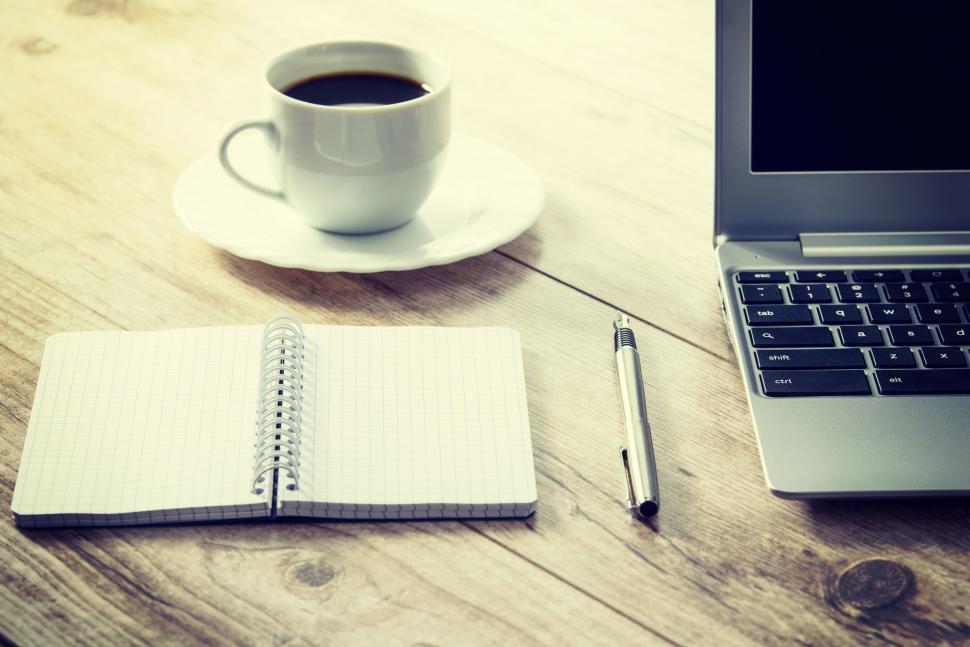 notebook and pen on desk with coffee